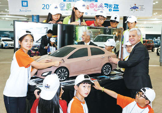 28일 한국지엠 부평 본사 홍보관에서 진행한 오토 사이언스 캠프 입소식에서 세르지오 호샤 한국GM 사장(오른쪽)이 이번 캠프에 참석한 학생들과 자동차 클레이 모형을 함께 살피며 담소를 나누고 있다.   한국GM 제공